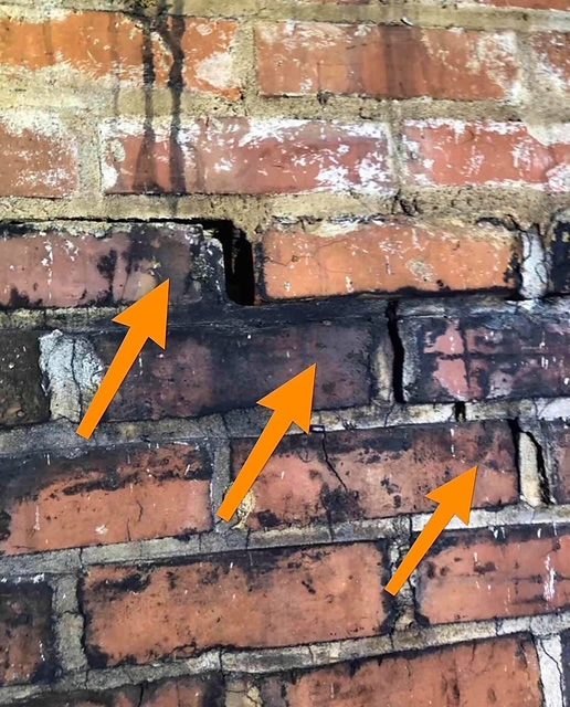 Stair-step cracking marked across a brick wall